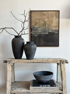 two black vases sitting on top of a wooden shelf