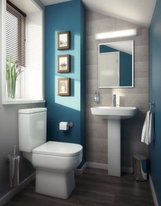 a white toilet sitting next to a sink in a bathroom under a window with blue walls