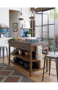 a kitchen island with pots and pans on it in front of an open window