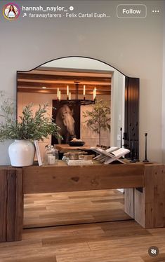 a mirror sitting on top of a wooden table next to a vase and potted plant