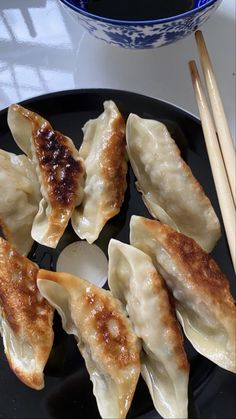 some dumplings and chopsticks on a black plate