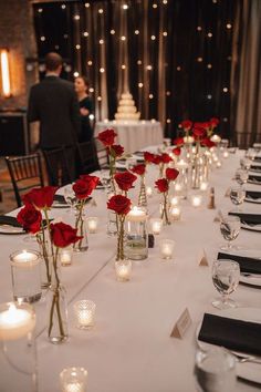 a long table is set with candles and roses in vases for centerpieces