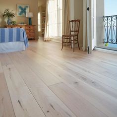 a bedroom with white wood floors and blue sheets on the bed, balcony overlooking the ocean