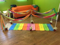 a room decorated with colorful ribbons and flower pots on the floor next to an orange couch