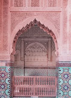 an intricately decorated building with blue and pink tiles on the walls, along with a wooden bench