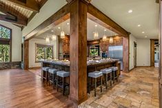 a large kitchen with an island and bar stools in the center, surrounded by wood flooring