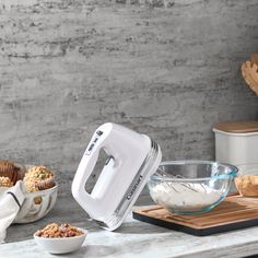 an electric mixer sitting on top of a counter next to bowls and muffins