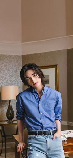 a young man is posing for the camera with his hands on his hips, wearing jeans and a blue shirt