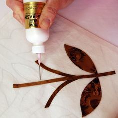 a person is using glue to decorate leaves