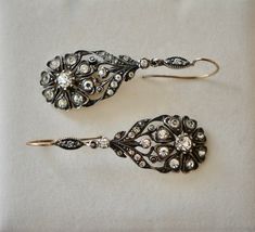 "Striking pair of English Victorian sterling and paste flower dangle earrings, circa 1840s - 1860s. The design is exquisite, comprised of a lovely daisy design of eight heart shaped petals with a larger round paste stone in the middle. There are also eleven more paste stones on the top of the earring. Materials - Sterling silver, paste stones and gold wire. Weight is 9.59 grams. Hallmarks - None. Condition - Very good antique condition. All stones are sparkling and clear. Measurements - Earrings Antique Drop Earrings With Historical Design, Victorian Drop Earrings For Vintage Events, Antique Earrings With Historical Design, Antique Wedding Earrings With Historical Design, Ornate Historical Design Earrings For Wedding, Ornate Historical Wedding Earrings, Vintage Rose Cut Diamond Earrings, Historical Design Earrings For Wedding, Ornate Wedding Diamond Drop Earrings