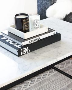 two books stacked on top of each other next to a coffee table with a candle