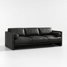 a black leather couch sitting on top of a white floor