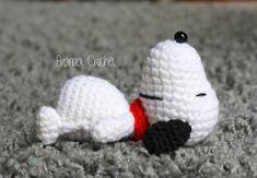 a crocheted white dog laying on top of a carpet next to a black ball