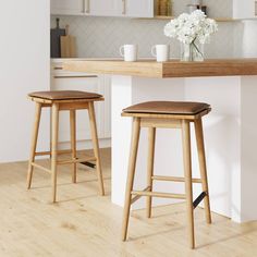 two wooden stools sitting in front of a counter top next to a vase with flowers