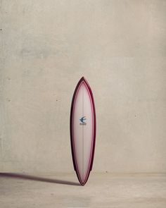 a white and red surfboard leaning against a wall