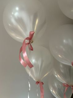 several white balloons with pink ribbons tied to them