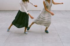 two women in long skirts are dancing on the floor