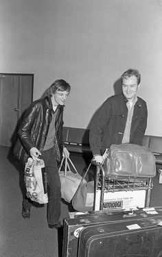 an old photo of two people pulling luggage