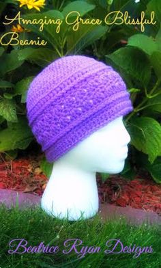 a white head wearing a purple crochet beanie on top of green grass