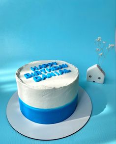 a white cake with blue frosting and the words happy birthday on it next to a dice