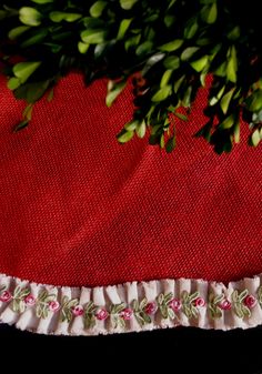 a close up of a red cloth with flowers on it and a plant in the background