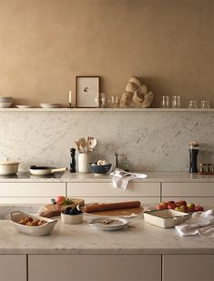 the kitchen counter is covered with dishes and bowls, including breadsticks, fruit, and other food items