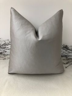 a gray pillow sitting on top of a white bed