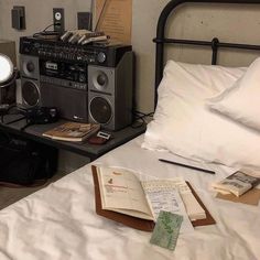 an old radio sitting on top of a bed next to a book and lamp,