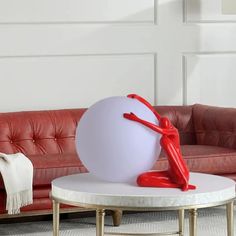 a red and white sculpture sitting on top of a coffee table next to a couch