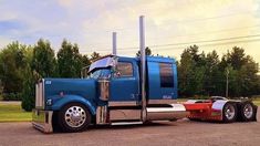 a large blue semi truck parked in a parking lot next to a red tractor trailer