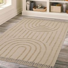 a beige rug with circles and fringes on the floor in front of a bookshelf