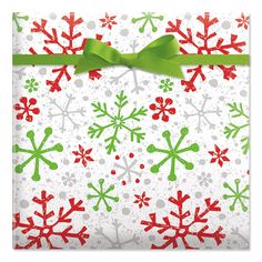 a christmas present wrapped in white paper with green ribbon and snowflakes on it