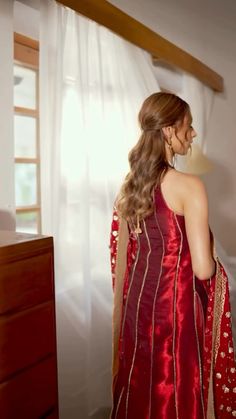 a woman in a red dress looking out the window