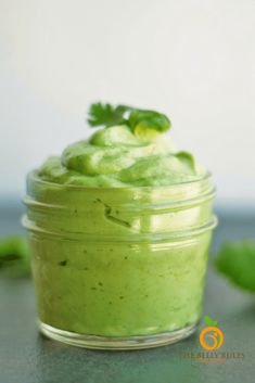 a small glass jar filled with green sauce and garnished with cilantro