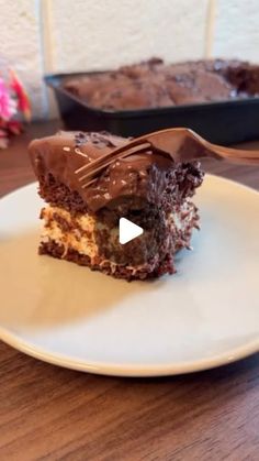 a piece of cake sitting on top of a white plate next to a pan filled with brownies