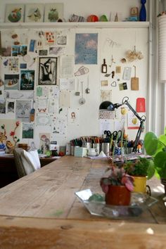 a wooden table topped with a potted plant next to a wall covered in pictures