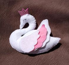 a white swan with a pink crown on its head sitting on a brown background,