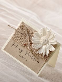 a card with a white flower on it sitting on top of a sheet of paper