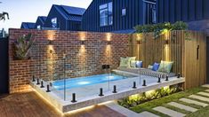 an outdoor swimming pool surrounded by brick walls and wooden steps with lights on the sides