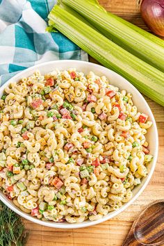 a white bowl filled with pasta salad next to celery