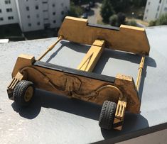 a toy car made out of wood sitting on top of a roof