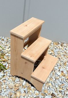 a wooden step stool sitting on top of gravel