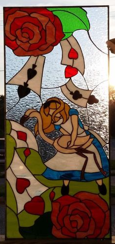 a stained glass window with roses and hearts on the bottom, in front of a body of water