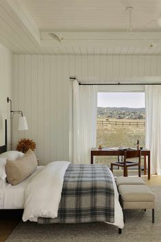 a bedroom with a bed, chair and desk in front of a large open window