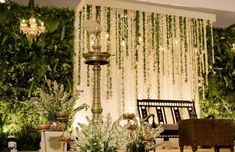 an outdoor wedding setup with flowers and greenery on the wall, chandelier in background