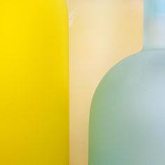 two vases sitting next to each other in front of a yellow and blue wall