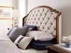 a bed with white and black pillows in a bedroom next to a dresser, coffee table and window