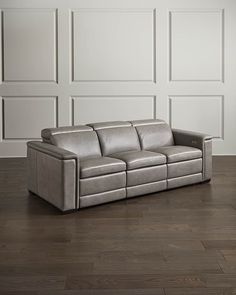 a grey leather couch sitting on top of a hard wood floor