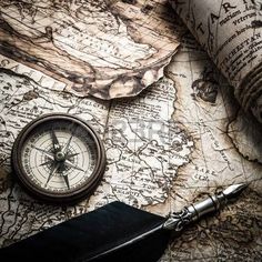 an old map, compass and pen on top of it