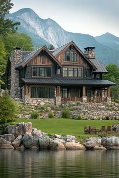 a large house sitting on top of a lush green field next to a lake and mountains